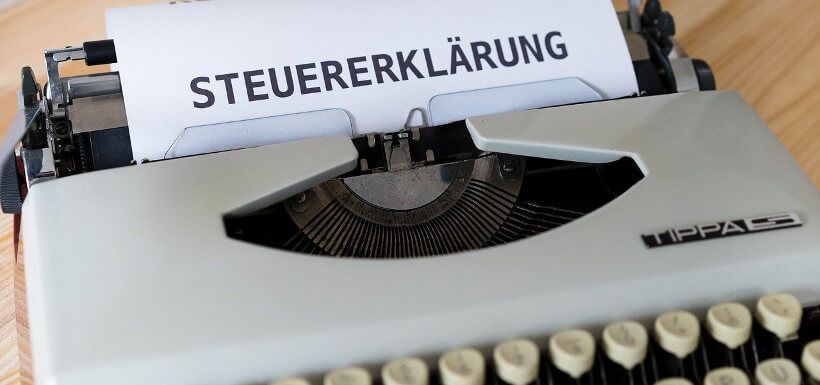 Blatt in Schreibmaschine zeigt in großen Buchstaben 